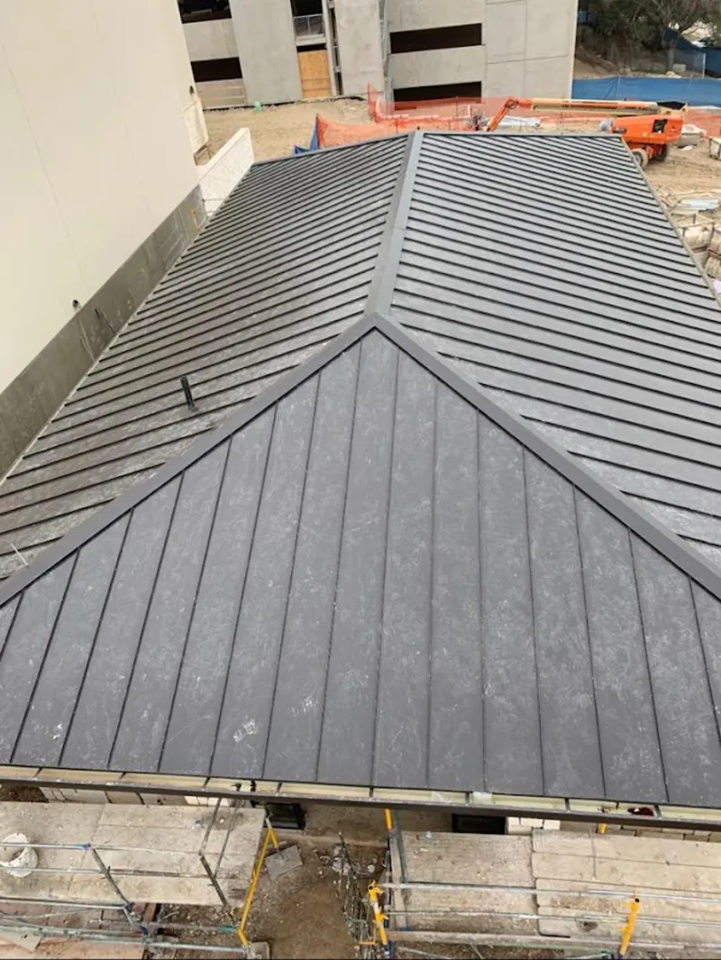 Commercial metal roof construction with crane equipment in Westport